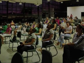 um grupo de mulheres sentadas em cadeiras observa alguém falar à sua frente